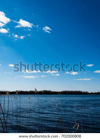 colorful clouds over the lake in summer with reflection of blue sky and trees  in water - vertical, mobile device ready image