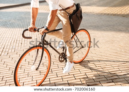 Cropped picture of young african handsome man early morning with bicycle walking outdoors.