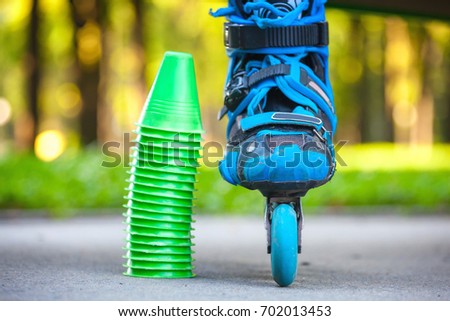 Close up of blue roller skates with cones lying on asphalt.