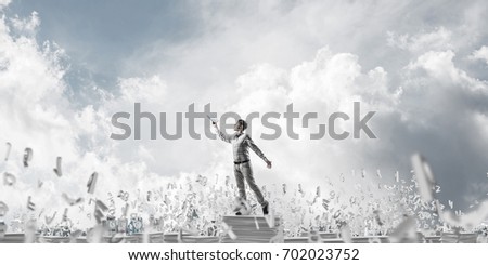 Man in casual wear keeping hand with book up while standing among flying letters with cloudly sky on background. Mixed media.