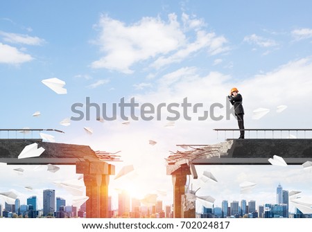 Engineer in suit and helmet looking in binoculars while standing among flying paper planes on broken bridge with cityscape and sunlight on background. 3D rendering.