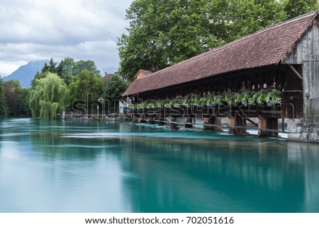Floodgate and old wooden bridge with beautiful flowers on the River Aare in the city of Thun, canton Bern, Switzerland. Long exposure photography