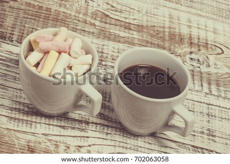 Black coffee in a white cup and marshmallows of different colors in a white cup