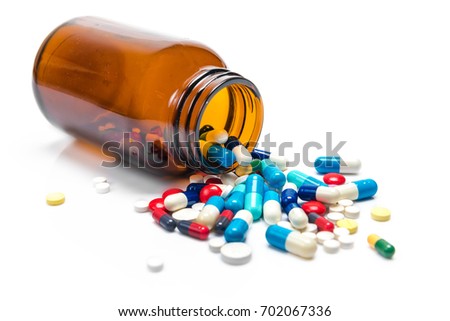 Pills spilling out of pill bottle on white background Royalty-Free Stock Photo #702067336