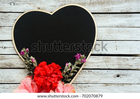 Love shape black board with Hibiscus flowers on a vintage white wooden background.