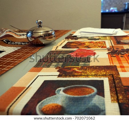 The tablecloth on the table with a Cup of coffee and a kettle