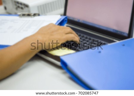 blurred man hand holding files document and typing computer keyboard notebook in work office 