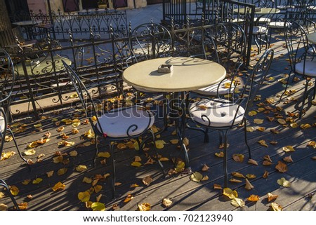 empty tables in street cafe in autumn with leaves