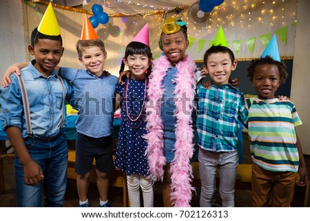 Portrait of smiling friends with arm around standing against wall during birthday party
