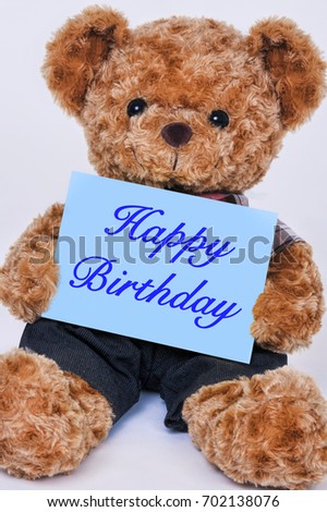Cute teddy bear holding a blue sign that reads Happy Birthday isolated on a white background