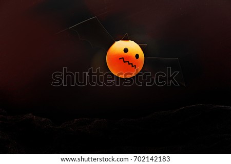 Bat cartoon made from a orange round ball on black scene in Halloween.