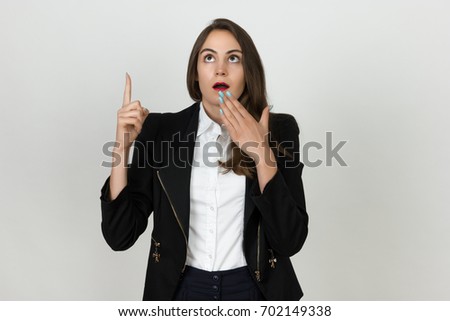 Young happy young businesswoman pointing up to product, isolated on gray background