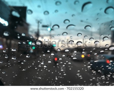 Blurred background, raindrop on the windshield, street light at night on a rainy day.