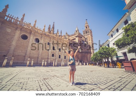 happy beautiful tourist girl in front of the Cathedral of Saint Mary of the See (Catedral de Santa María de la Sede), better known as Seville Cathedral