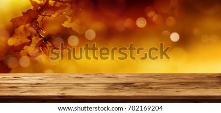 Golden autumn leaves with bokeh and empty wooden table for a background decoration
