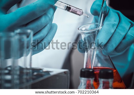 Conical flask in scientist hand with lab glassware background, Laboratory research concept Royalty-Free Stock Photo #702210364