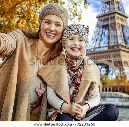 Autumn getaways in Paris with family. smiling mother and daughter tourists on embankment near Eiffel tower in Paris, France taking selfie