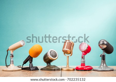 Retro old microphones for press conference or interview on table front gradient aquamarine background. Vintage old style filtered photo Royalty-Free Stock Photo #702235132