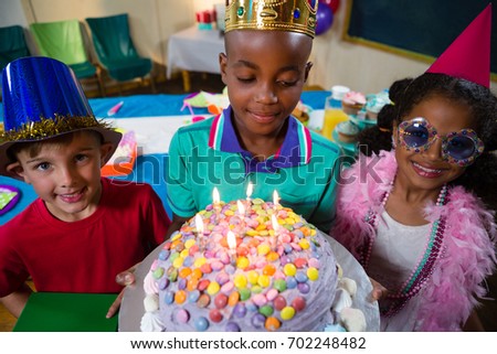 High angle view of boy holding birthday cake while standing with friends