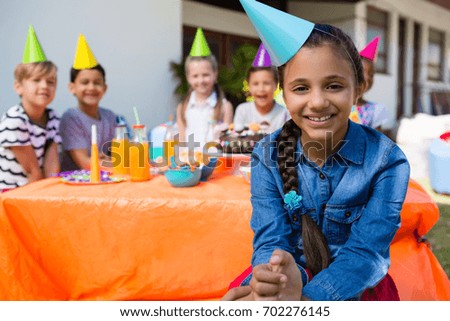 Portrait of happy girl with friends in background during birthday party