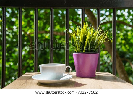espresso coffee in white cup on the wooden table with small mock up plant at terrace or balcony of hotel with garden view. coffee, relax, holiday, feel good or thinker concept.