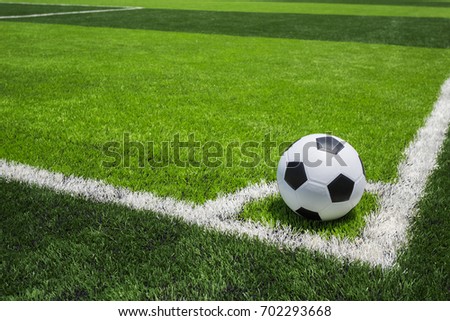 Classic soccer ball on artificial bright and dark green grass at public outdoor football or futsal stadium Royalty-Free Stock Photo #702293668