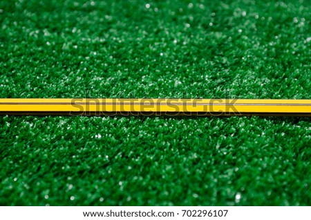 yellow pencil on artificial grass background