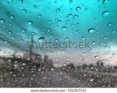 Blurry background, raindrops on the windshield, windshield view on a rainy day.