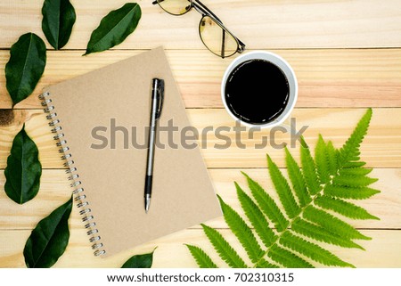 a book with green leaves on wooden table