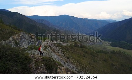 Aerial. traveler on the edge of the cliff enjoying the beautiful view. girl tourist in mountain. Altai, Siberia. Aerial camera shot
