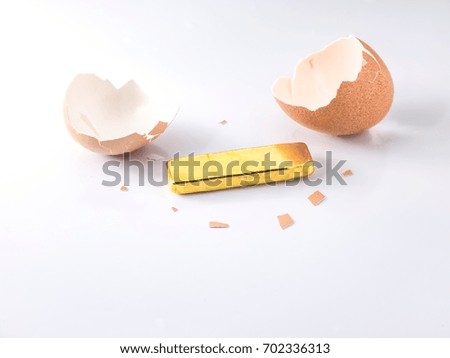 Yellow gold bar inside cracked eggshell on white background