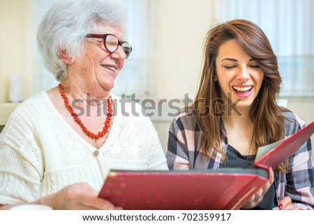 Grandmother and granddaughter looking at old photos at photo album.