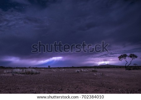 Lightning over desert, three lightnings at the same time, grass desert in Australia, outback Royalty-Free Stock Photo #702384010