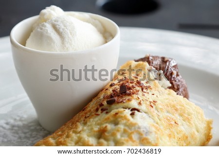 Close-up of a plated chocolate pancake served with ice-cream on a white plate (shallow depth of field)