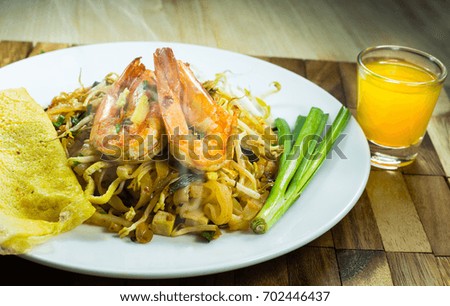 Thai food noodle and shrimp with orange juice on wood, PAD THAI style food with smoke on food on table