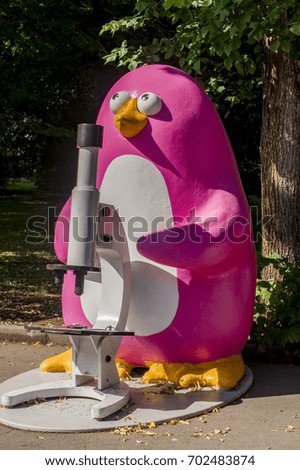 colorful statue of penguin with microscope in city garden 