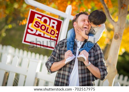 Young Mixed Race Chinese and Caucasian Father and Son In Front of Sold For Sale Real Estate Sign and Fall Yard.