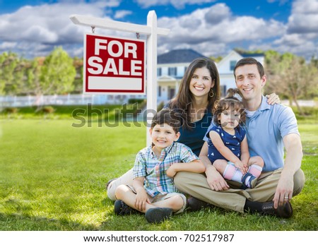 Young Family With Children In Front of Custom Home and For Sale Real Estate Sign.