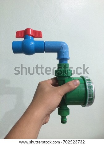 Hand holding Water pump control with timer, white background, irrigation system.