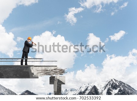 Young engineer in suit and helmet looking in spyglass while standing on broken bridge with skyscape and nature view on background. 3D rendering.