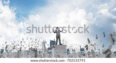 Businessman in suit standing among flying letters with speaker in hand and with skyscape on background. Mixed media.