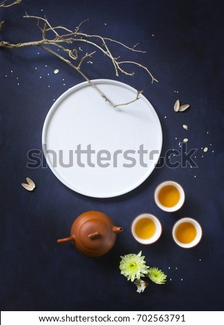 Traditional mid autumn festival celebration tea time image. Big bright moon form by a white plate, flying insects form by pumpkin seeds. Flat lay conceptual text space image. Royalty-Free Stock Photo #702563791