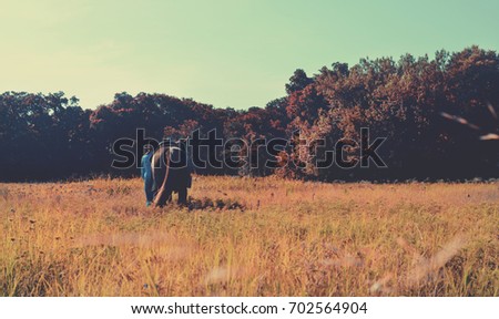 Rustic fall color background with cowgirl walking horse through pasture, western ranch equestrian image in autumn.