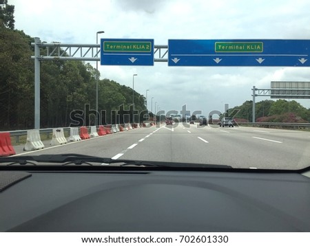 Dashboard Of A Car Driving In A Highway With Road Signage In View