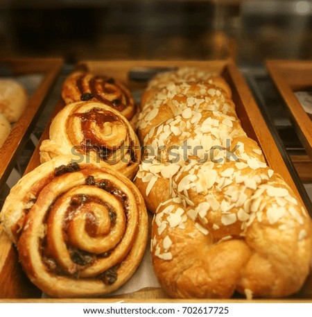Cinnamon Roll & Almond Croissant fresh homemade bakery on the wood tray in a warm light tone. To present on the menu of bakery or dessert at the coffee shop restaurant. Wallpaper &  Picture decoration