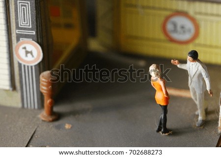 Miniature figure plastic model toy of man and woman put on the model town scene.