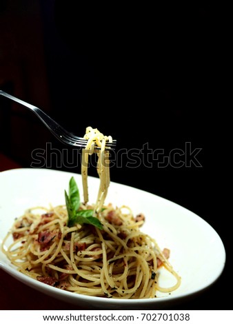 The picture of Spaghetti With Dried Chili And Bacon on white dish. selective focus.  black background