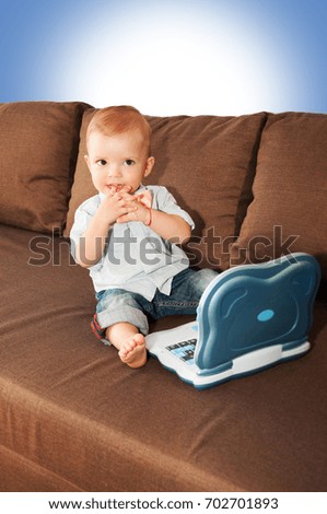 1 year old baby sitting on sofa with laptop
