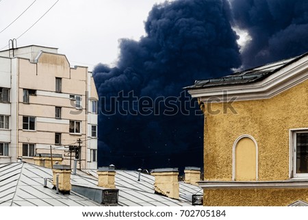 Black smoke from a fire is over the roofs of houses