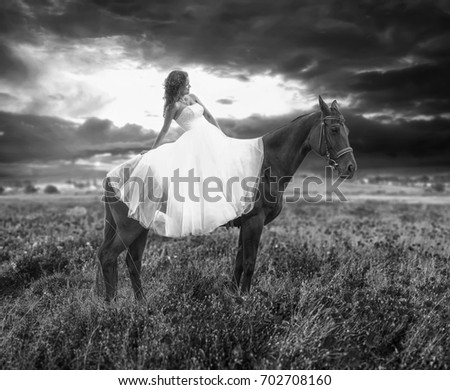 Beautiful bride, lying on a horse on her wedding day. Black and white high contrast picture
